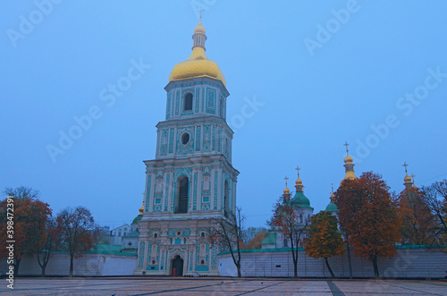 Beautiful wide-angle landscape photo of ancient Saint Sophia Cathedral against rainy sky. Christian orthodox cathedral. Belfry in shrouded in fog. Misty autumn morning in Kyiv, Ukraine.Travel concept