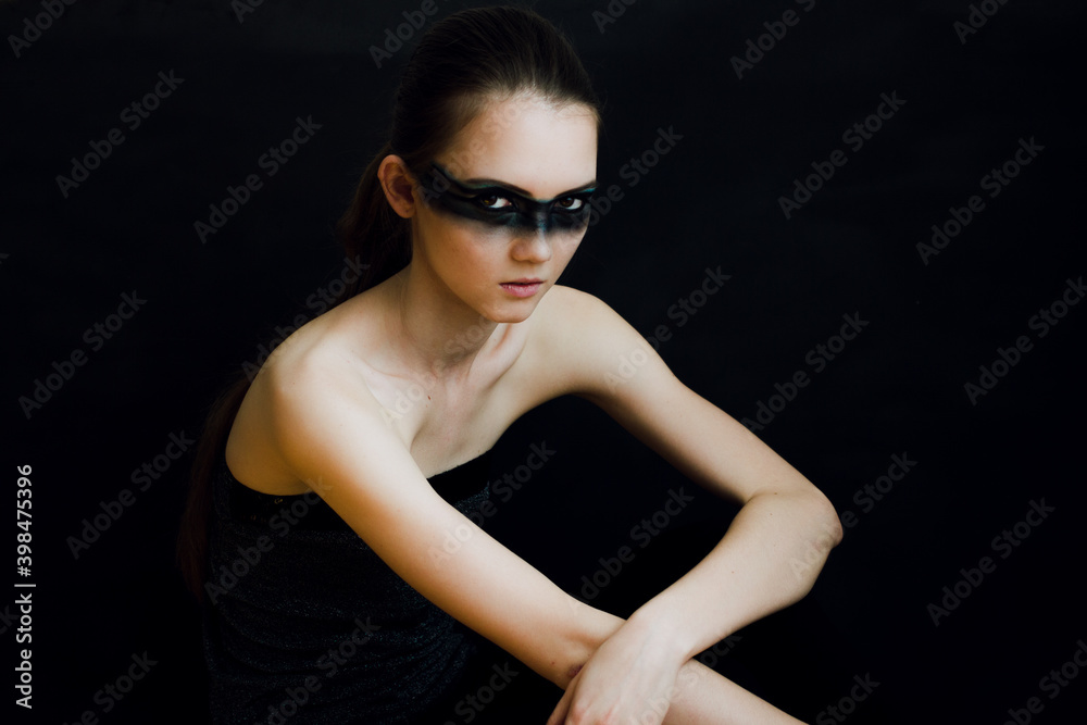 Young woman with makeup and a fashionable hairstyle poses in studio on black background Young woman with makeup and a fashionable hairstyle poses in studio on black background