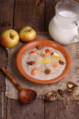 Oatmeal with milk, nuts and apples on a wooden table