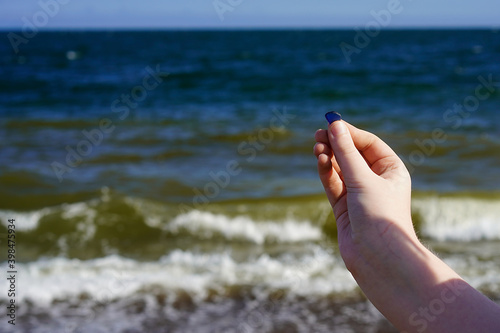 Child's hand with sea glass on the sea background. © vvicca