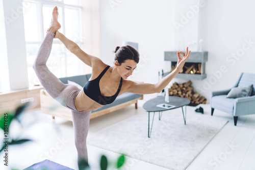 Tranquil Caucasian female in activewear relaxing in Natarajasana keeping healthy lifestyle and wellness, flexible woman enjoying sport and yoga training perfect body shape for mindfulness vitality