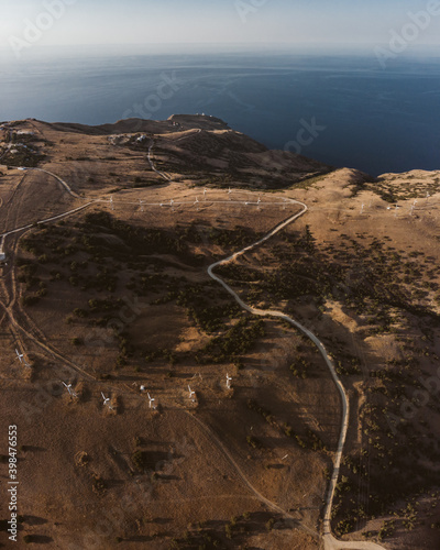Aerial drone panorama shot of mountain area, windmills, the long and winding road through the mountains. Southern region, sands, desert 