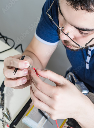 computer repairman repairing components of electronic device. young man repairs a tablet.