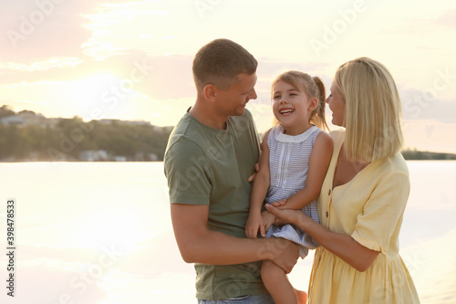 Happy parents with their child on beach, space for text. Spending time in nature