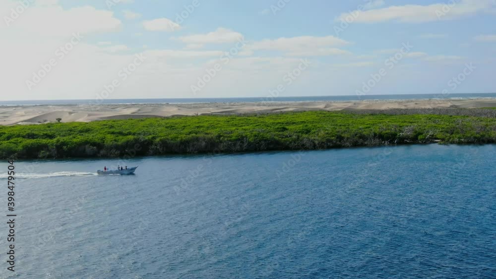 Aerial view moving right shot, Boat moves along the river in La Purisima, Baja California sur, Mexico, Scenic view mangrove forest and desert in the background. Aerial view moving right shot, Boat moves along the river in La Purisima, Baja California sur, Mexico, Scenic view mangrove forest and desert in the background.