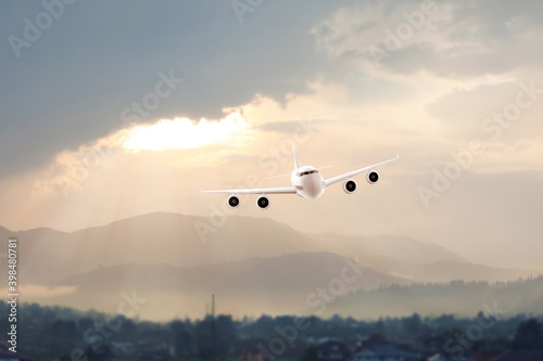 Modern airplane flying in cloudy sky over hills