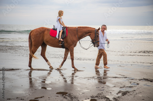 Little pretty girl on a horse. Father leading horse by its reins on the beach. Horse riding by the sea. Family concept. Father's day. Summer holidays. Bali, Indonesia
