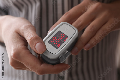 Woman measuring oxygen level with modern fingertip pulse oximeter, closeup