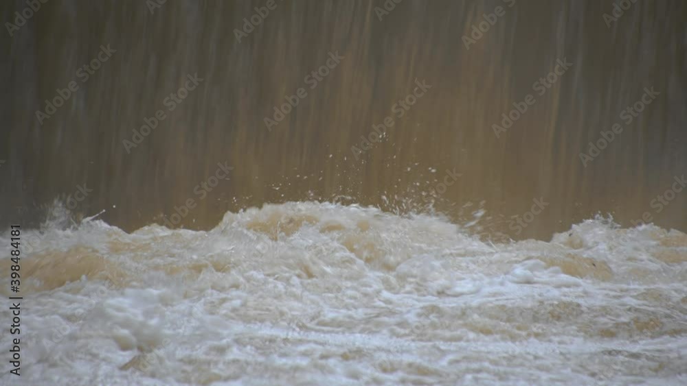 Close up view of raging muddy waterfall. Alpine river floods after heavy rain. Close up, real time, low angle Close up view of raging muddy waterfall. Alpine river floods after heavy rain. Close up, real time, low angle