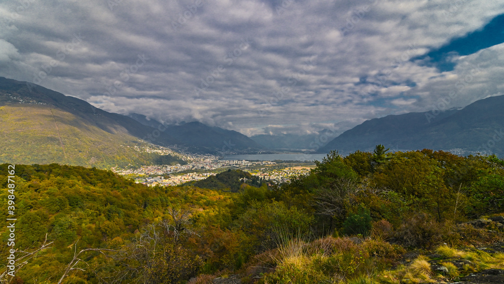 Veduta dall'alto di una cittadina, in autunno, con cielo nuvoloso ma alberi dei colori arancioni dell'autunno