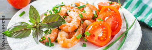 Grilled  shrimps or prawns with tomatoes and basil in a plate on a table. Banner