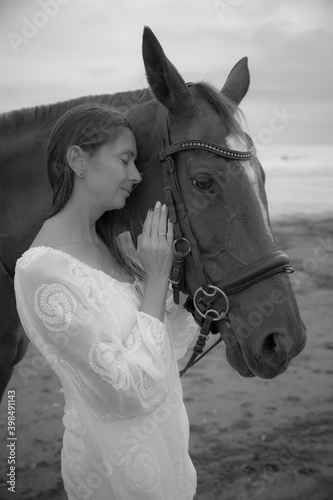 Monochrome. Portrait of beautiful woman and horse. Caucasian woman hugging and stroking horse. Black-white photo. Love to animals. Beach in Bali, Indonesia