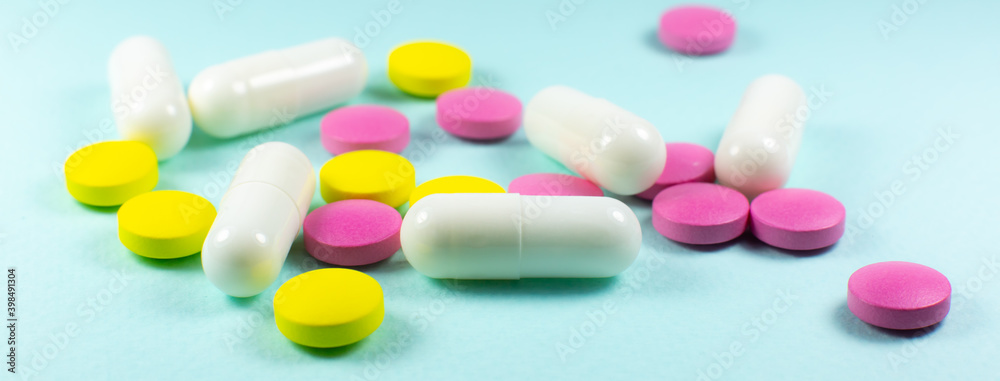 Colored pills and tablets on green background. Close up. Medical treatment concept.