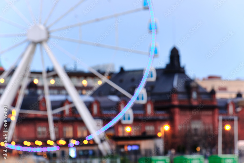 Blurred view of Ferris wheel and historical neighborhood of Helsinki in the evening.