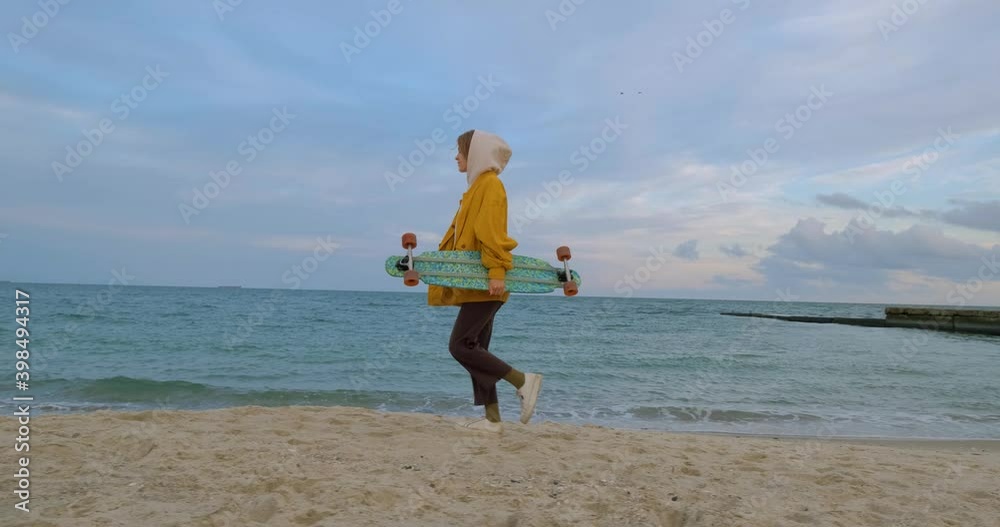 Happy young woman on the beach with longboard skateboard 