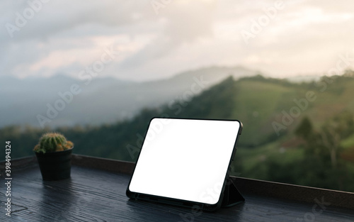 Front view of cup and tablet on table in Office park and blurred background of trees in the forest