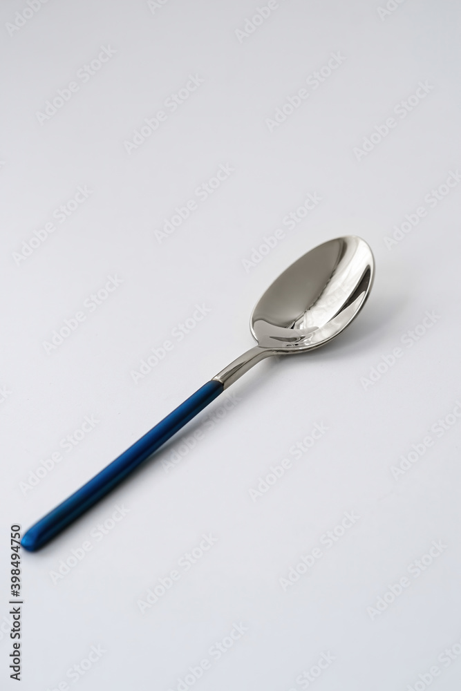 Silver or steel cutlery on an isolated background. Gilded teaspoon of blue color. Top view. Silver or steel cutlery on an isolated background. Gilded teaspoon of blue color. Top view.