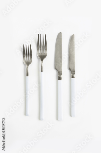 White silver or steel cutlery view from above on a white background. Top view..Knife and fork for a festive table for a wedding  birthday or party.