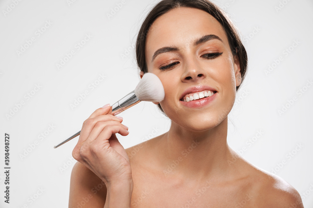 Beautiful shirtless happy girl smiling while using powder brush Beautiful shirtless happy girl smiling while using powder brush