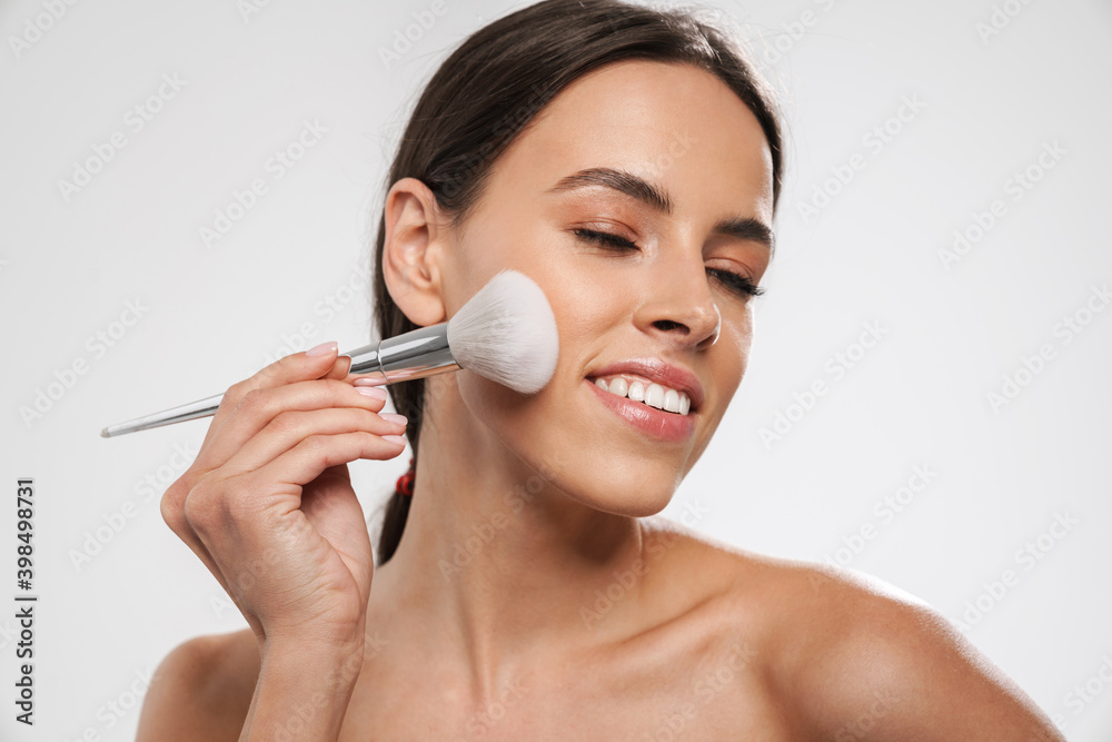 Fototapeta premium Beautiful shirtless happy girl smiling while using powder brush