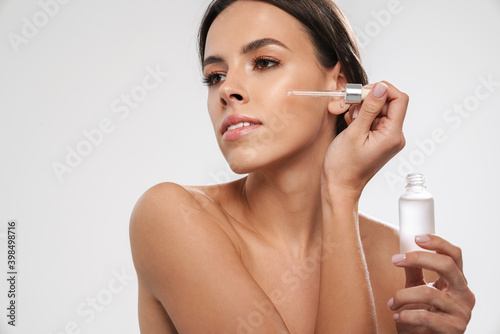 Beautiful shirtless seductive girl applying face serum