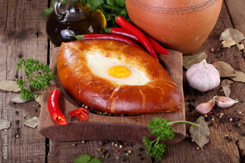 Adjar Khachapuri, cheese pie with cilantro, pepper and garlic on a wooden table photo