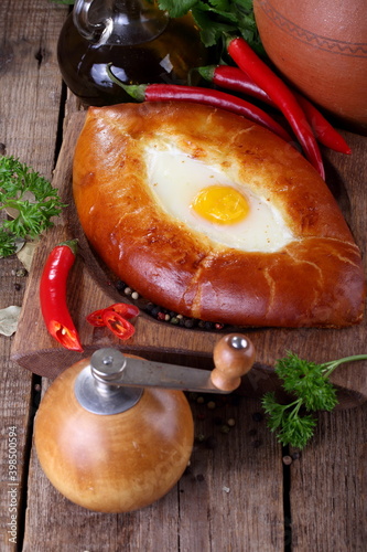 Adjar Khachapuri, cheese pie with cilantro, pepper and garlic on a wooden table photo