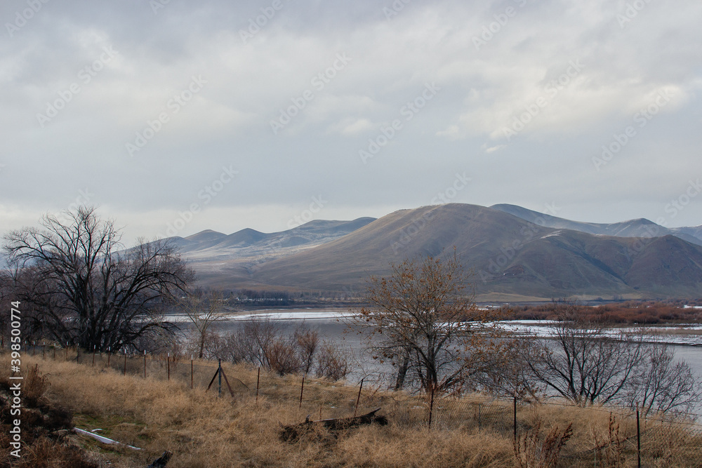 Fototapeta premium Beautiful winter landscape with snow-covered mountains, dry grass and a river in the foreground. Huntington, OR, USA