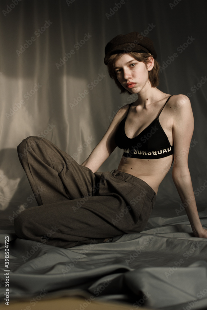Naklejka premium portrait of a young woman in in trousers and a top. Model with hat and short hair. Natural clean face