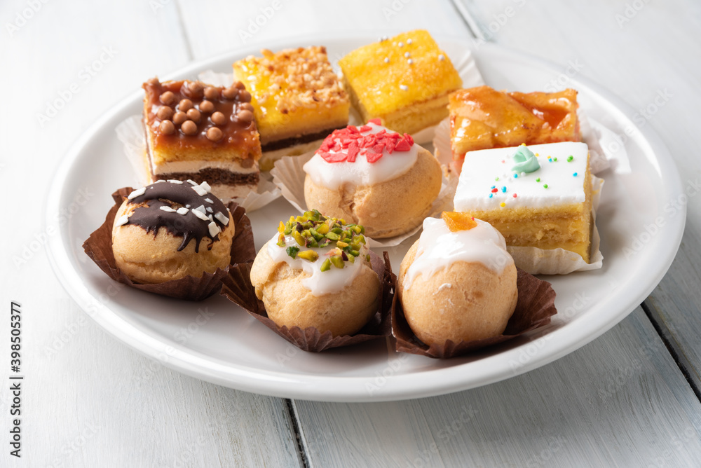 Piatto con deliziosi bigne e pasticcini assortiti Piatto con deliziosi bigne e pasticcini assortiti