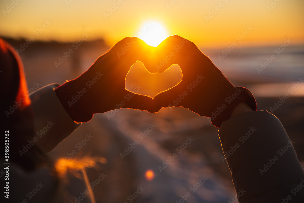 Woman hands in red winter gloves Heart symbol shaped Lifestyle, Winter Solstice and Feelings concept with sunset light nature on background - obrazy, fototapety, plakaty 