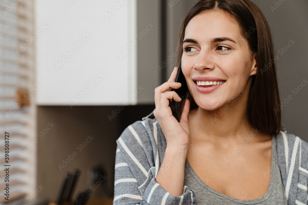 Charming happy woman smiling while talking on mobile phone Charming happy woman smiling while talking on mobile phone
