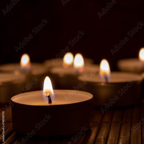 candles in the dark with copy space. Close up of many tea lights in the night 