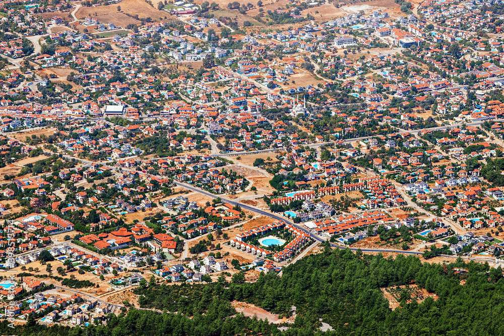 Aerial view of a Turkish suburban quarter with new homes in a resort area on the Mediterranean coast with swimming pools and a mosque in the distance.