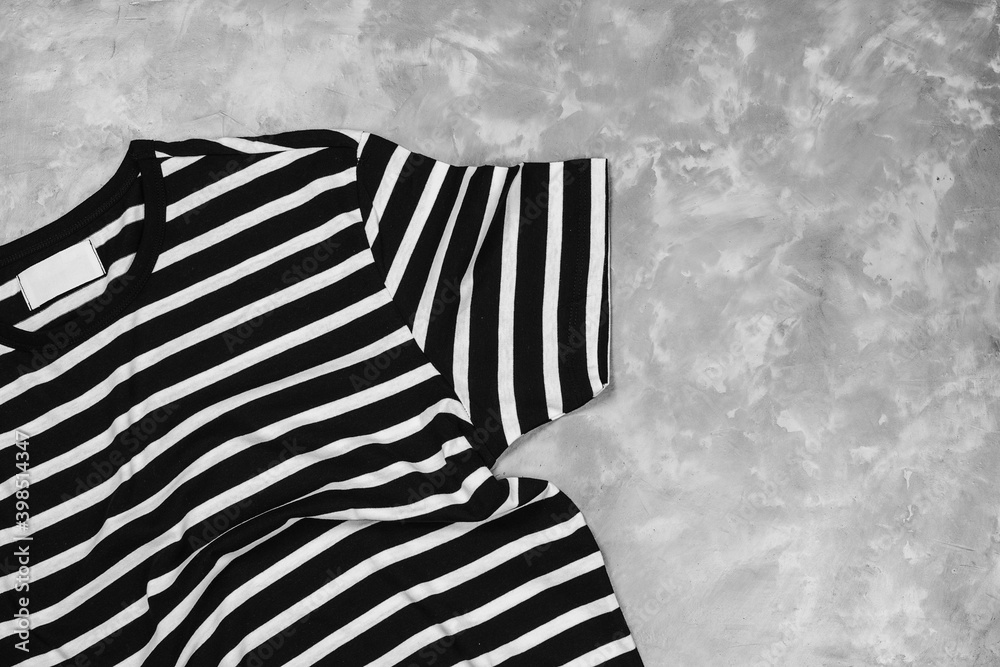 Striped black and white t-shirt mockup, flat lay. Modern t-shirt on concrete grey background Striped black and white t-shirt mockup, flat lay. Modern t-shirt on concrete grey background