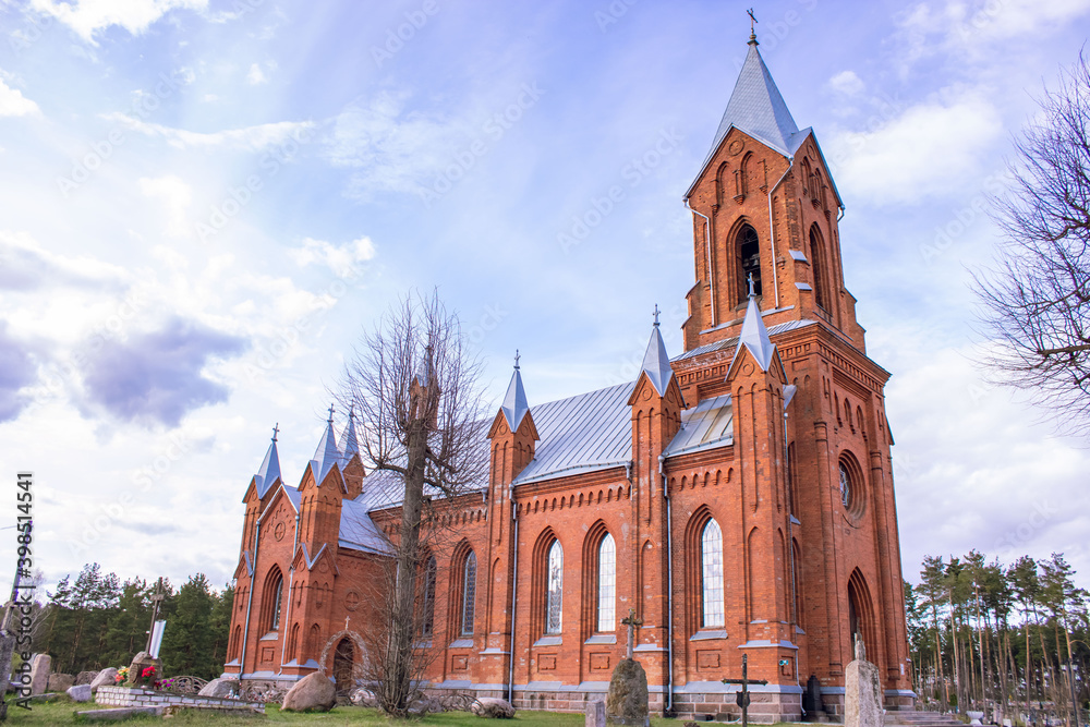 Fototapeta premium Red brick church in the sun. Church of St. Alexei in the town of Ivenets, Belarus