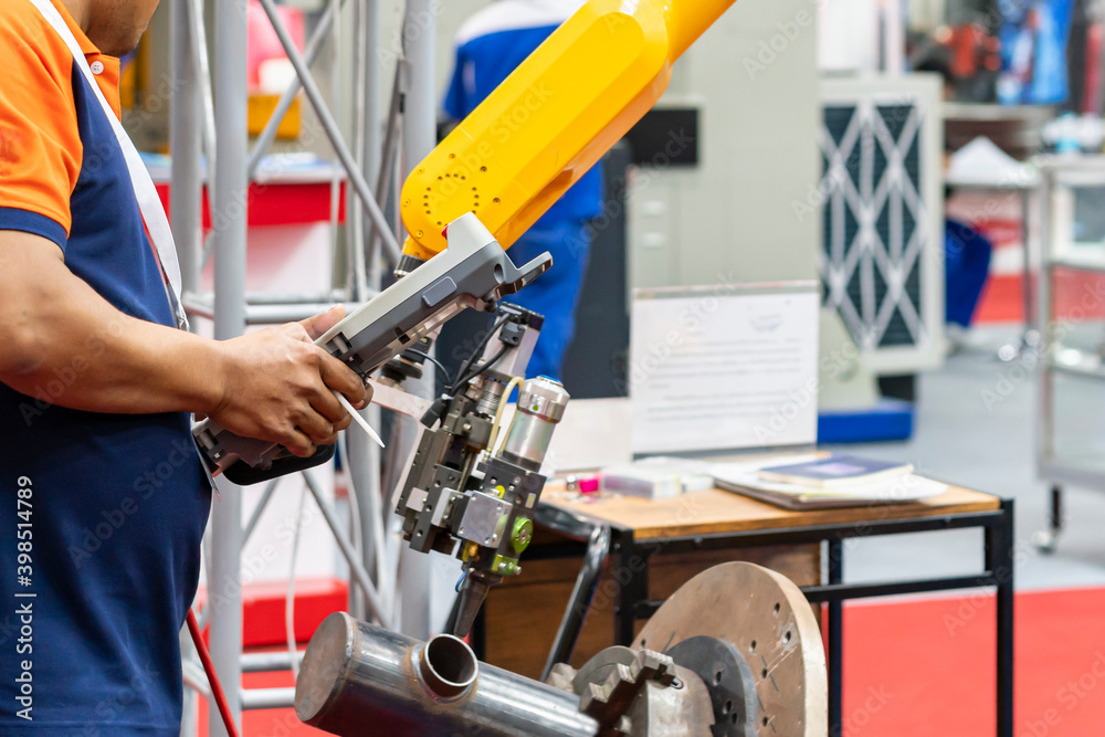 Fototapeta premium man or technician enter command information pass wireless remote for control automatic robot arm to do welding work in production
