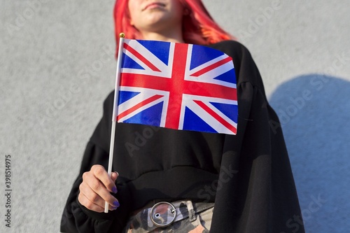 Female student teenager with British flag, gray outdoor wall background