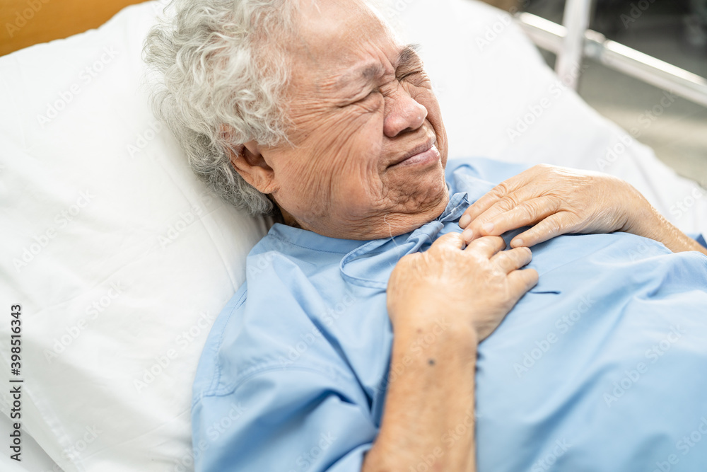 Fototapeta premium Asian senior or elderly old lady woman patient feel pain in the chest and heart on bed in nursing hospital ward; healthy strong medical concept.