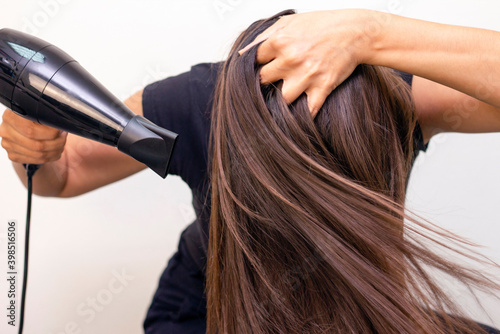 beautiful young woman with long, smooth brown hair looks after her hair. self-drying hair