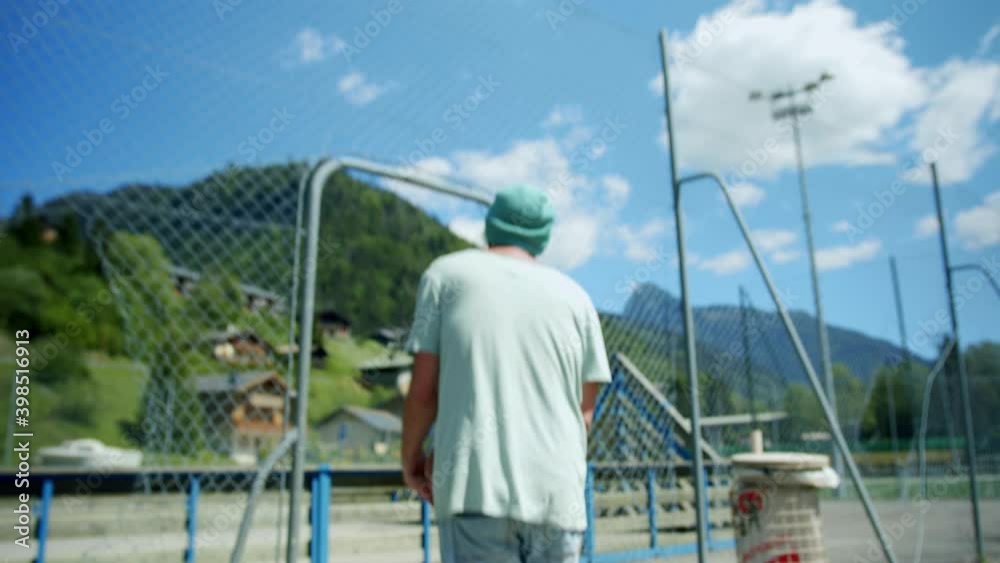 A man walks onto an outdoor basketball court A man walks onto an outdoor basketball court