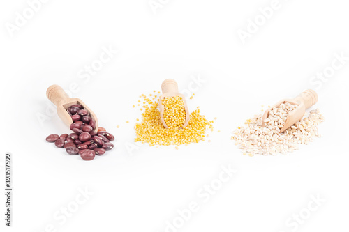 Studio lighting. White background. Close-up of cereals. Millet, red beans, pearl barley are placed in a wooden spice spoon. photo