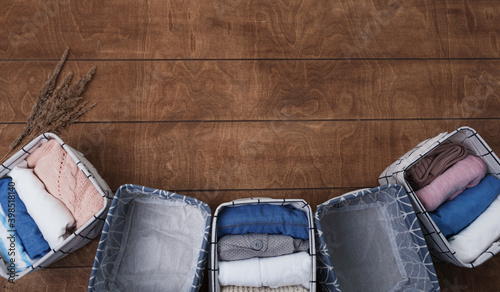 A group of organic cotton clothing laid out on a wooden background is ready to be folded into white baskets.The concept of closet organization.using the komari method. photo