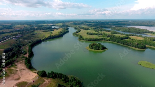 Aerial view of of small islands on a blue lake Saimaa. Landscape with drone. Blue lakes, islands and green forests from above on a cloudy summer morning.