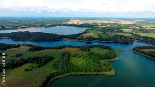 Aerial view of of small islands on a blue lake Saimaa. Landscape with drone. Blue lakes, islands and green forests from above on a cloudy summer morning. © Егор Павлющик