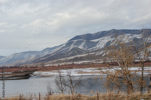 Beautiful winter landscape with mountains, river, and dry yellow glass. Panorama. Huntington, OR, USA