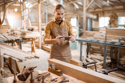 Fotografi Carpenter with phone in the workshop