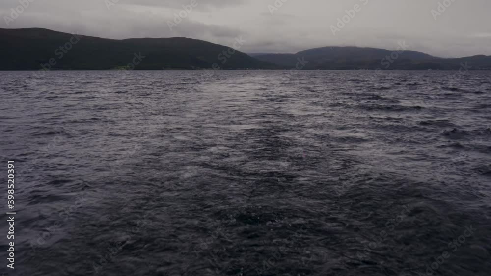Water trail of a boat in a dark blue ocean in Norway Water trail of a boat in a dark blue ocean in Norway
