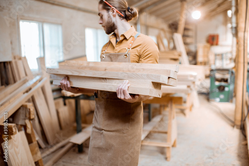 Carpenter carrying pine planks in the warehosue photo