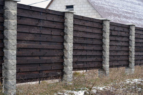 Close board fence erected around a garden for privacy with wooden fencing panels, concrete posts and kickboards for added durability. © Алексей Ковалев